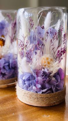 two glass vases with flowers and feathers in them