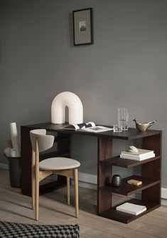 a desk with two chairs and a vase on it in a room that has gray walls