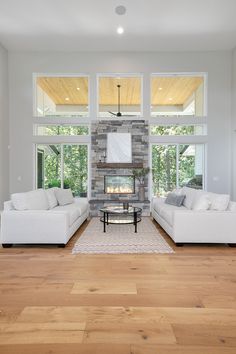 a living room with two white couches and a fireplace in the middle of it