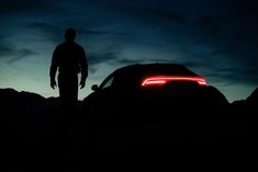 a man standing next to a car in the dark