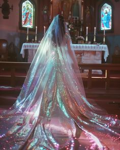 a woman in a wedding dress standing at the alter with her veil draped over her head