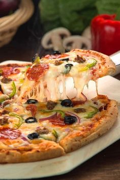 a pizza being lifted with a spatula from a white plate on a wooden table