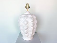 a white vase sitting on top of a metal shelf next to a light bulb holder