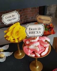 some candies are sitting on top of each other in gold dishes and signs that read, dentiste de bruxa