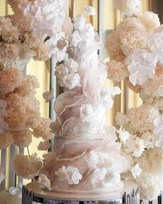 a wedding cake with white flowers on the top and bottom is surrounded by other decorations