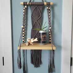 a wooden shelf holding a can and some tassels hanging from it's sides