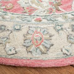 a pink and white rug on top of a wooden floor with a wood floor in the background