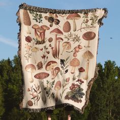 a blanket with mushrooms and leaves on it hanging from the side of a wooden pole