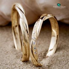 two gold wedding bands with diamonds on the top and bottom, sitting next to each other