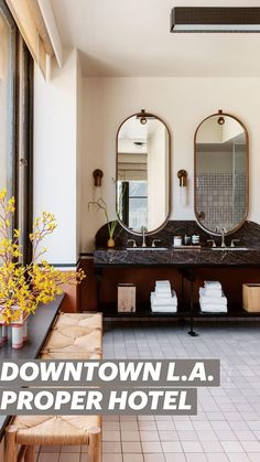 a large bathroom with two sinks and mirrors on the wall, along with a bench in front of it