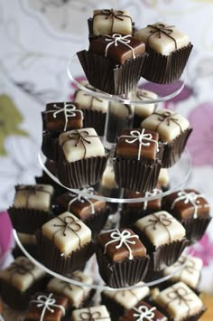 there are many small cupcakes stacked on a cake stand with white and brown icing