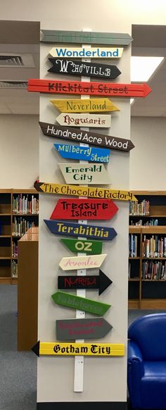 there are many different signs on the wall in this library, and one has a blue chair next to it