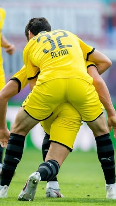 two men in yellow uniforms are playing soccer