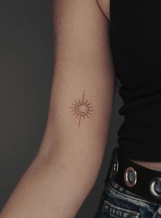 a woman's arm with a small sun tattoo on the back of her left arm