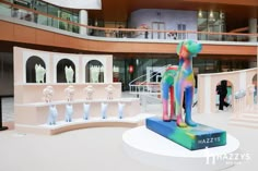 an art exhibit with colorful sculptures in the center and people walking around it onlookers