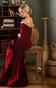 a woman in a red dress is sitting on a chair and looking off to the side