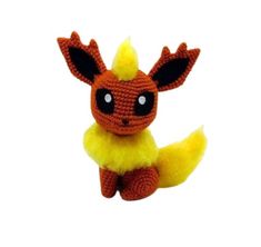 a crocheted pokemon stuffed animal sitting on top of a white surface and looking at the camera