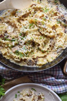 a pan filled with pasta and mushrooms on top of a table next to two plates