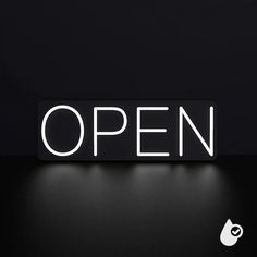 an open sign is lit up in the dark with white letters on it and a black background