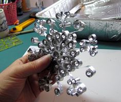 a person holding up a bunch of silver beads on top of a white countertop