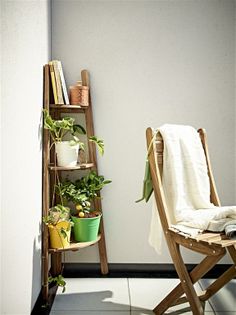 a wooden chair sitting next to a shelf with potted plants on top of it