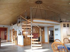 a spiral staircase in the middle of a room with wooden chairs and tables around it