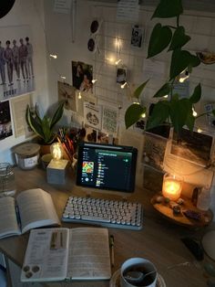 an open book on a desk next to a keyboard and monitor with a lit candle