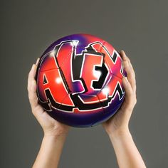 a person holding a basketball in their hands with the letters x and e painted on it