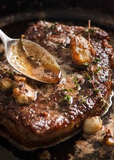 a spoon is being used to scoop some food out of the skillet on top of steak