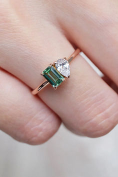 a woman's hand holding an emerald and diamond ring