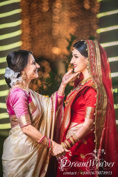 two women dressed in red and gold standing next to each other with lights behind them