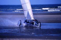 a sailboat that is sitting in the water at the beach with it's sails down