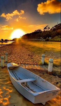 a small boat sitting on top of a sandy beach