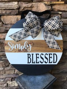 a wooden sign that says simply blessed with two large bows on the front of it