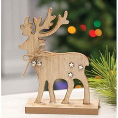 a wooden reindeer ornament sitting on top of a table next to a christmas tree