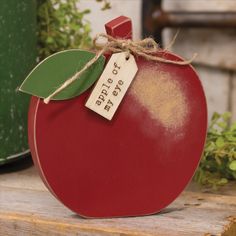 a red apple sitting on top of a wooden table next to a potted plant