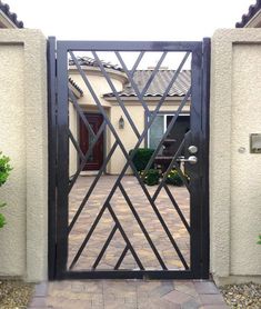 an iron gate in front of a house that has a brick walkway leading to it