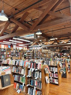 the inside of a book store with many books on shelves and wooden beams above them