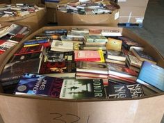 a cardboard box filled with lots of books on top of a floor next to boxes