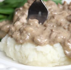 a white plate topped with mashed potatoes covered in gravy