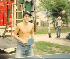 a shirtless man holding a ping pong paddle