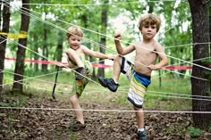 two young boys playing in the woods with tennis racquets and ball net