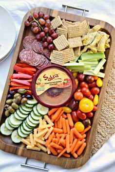 a platter filled with crackers, vegetables and fruit