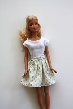 a barbie doll with blonde hair wearing a white top and blue polka dot print skirt