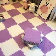 two stuffed animals sitting on the floor in front of pictures and rugs that are purple and white