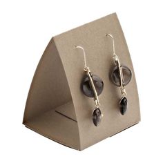 a pair of earrings is displayed on a display stand, with one earring dangling from the back