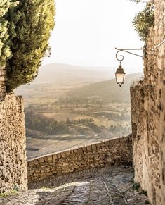 an alley way with stone walls and cobblestone streets leading to the valley below