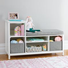 a white shelf with baskets and stuffed animals on it in a child's room