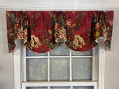 the window is decorated with red and green flowers on it's valance,