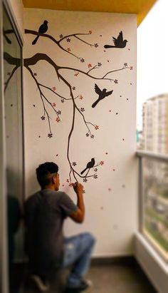 a man is painting a tree with birds on it